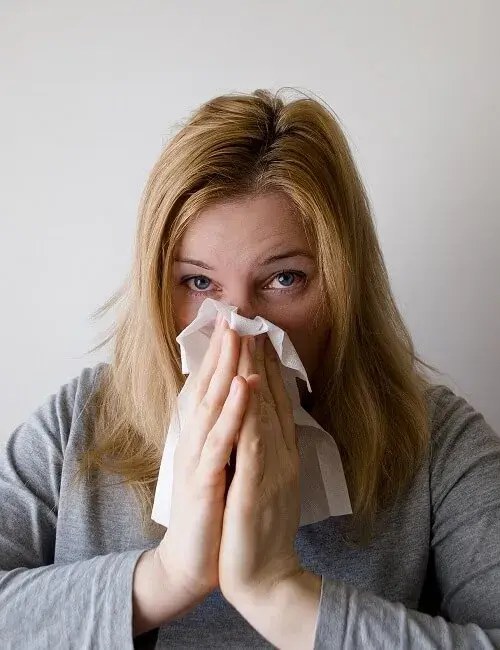 Verkouden vrouw met griep snuit haar neus