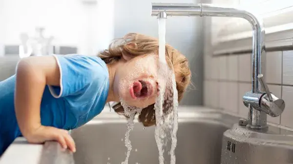 Barn som dricker vatten ur kran