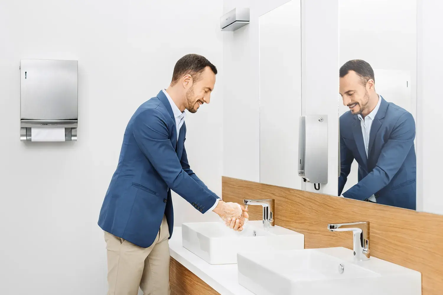 Ein Mann wäscht sich seine Hände in einem mit CWS-Produkten ausgestattetem Bad.