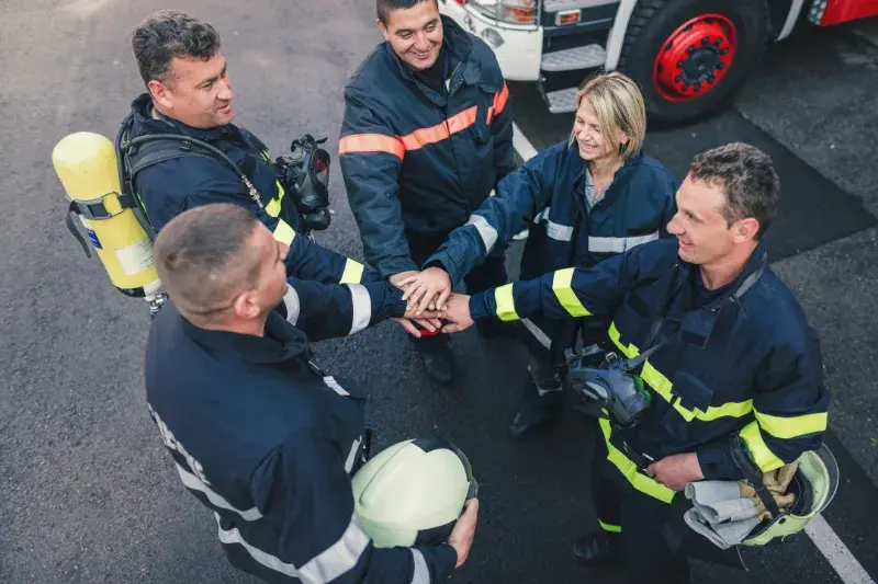 5 firefighters hold hands over each other in the middle
