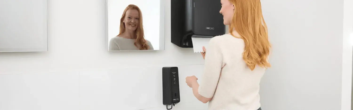A woman dries her hands in front of the mirror