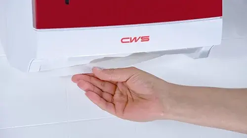 Iemand pakt een papier uit een handdoekdispenser om handen af te drogen
