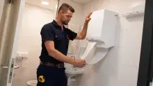 Een CWS handdoekautomaat wordt bediend door een Schoonster medewerker