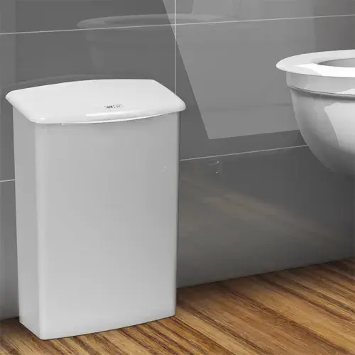 Biely hygienický kôš od spoločnosti CWS stojí vedľa toalety.