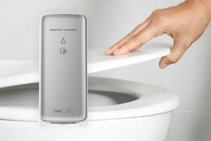 Eine WC-Brille wird von einer Hand hochgehoben, im Vordergrund des Bildes befindet sich ein CWS Spender mit Toilettensitzreiniger