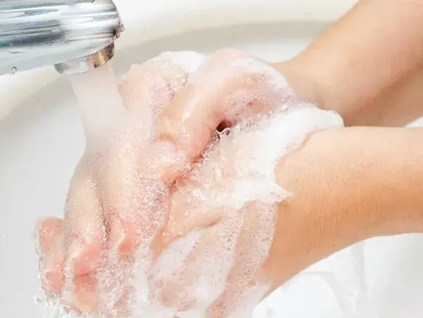 Dvě namydlené ruce se opláchnou pod tekoucí vodou.