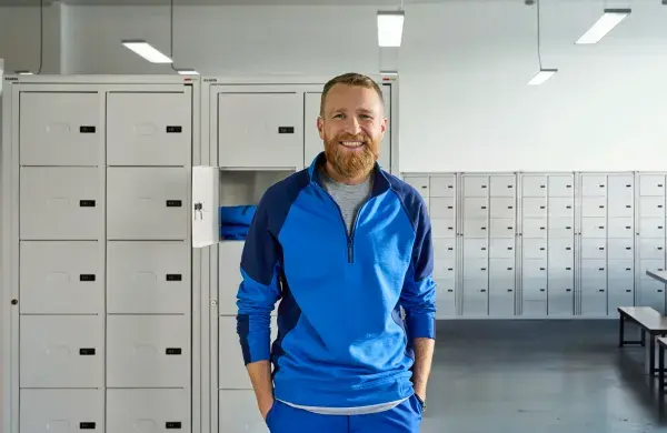 A man wearing bright yellow hoodie and standing in front of the locker system