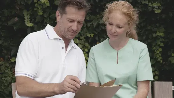 Två personer iklädda vårdkläder tittar på en skärm