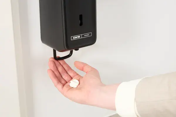 A black hand lotion dispenser from CWS PureLine EcoBlack with a hand with hand lotion on